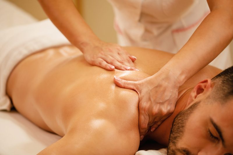 Close-up of man having back massage during spa treatment at wellness center.